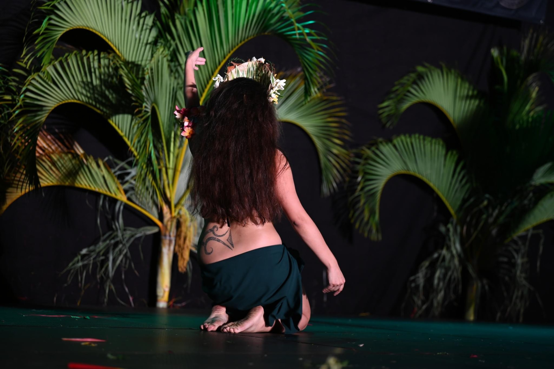 Bailarina de rodillas entre palmeras en escena